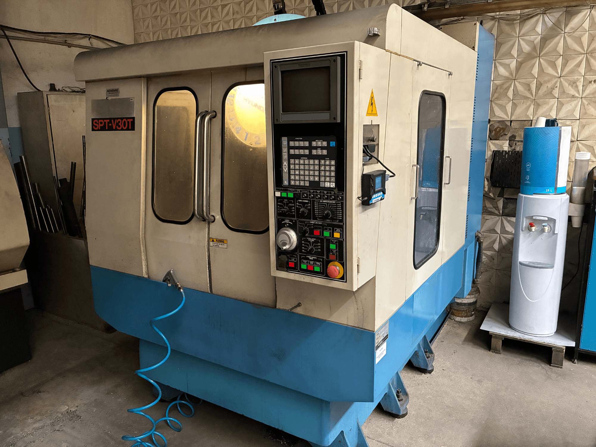 Fresadora industrial SPT-V30T, vista frontal, con un panel de control, botones y una manguera azul.