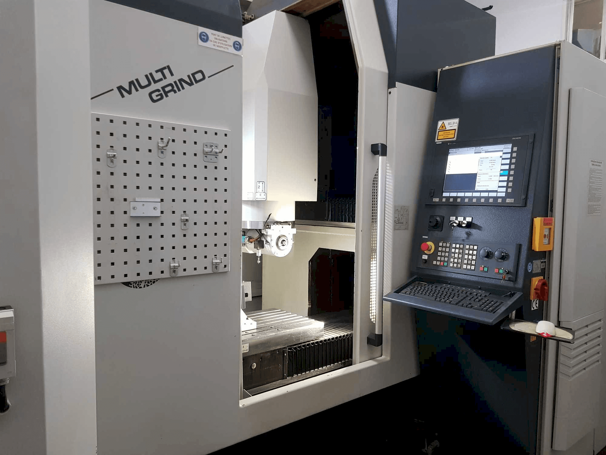 Máquina CNC Multi Grind con vista frontal, con panel de control, tablero de clavijas de almacenamiento y área de trabajo abierta.